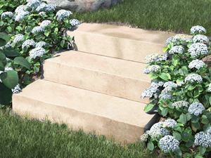 Bloktrin i kalksten Camino Sand med blomster og buske