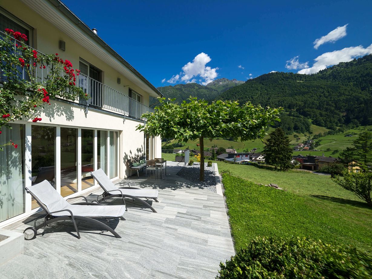 Terrasse med granitplader, liggestole og bjerge i baggrunden