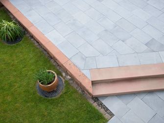 Kalkstensterrasse med græs og planter