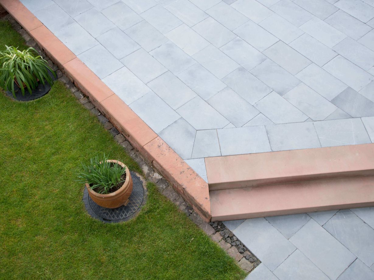 Blaustein Azur harmonerer med mange farver. Kalkstensterrasse med græs og planter