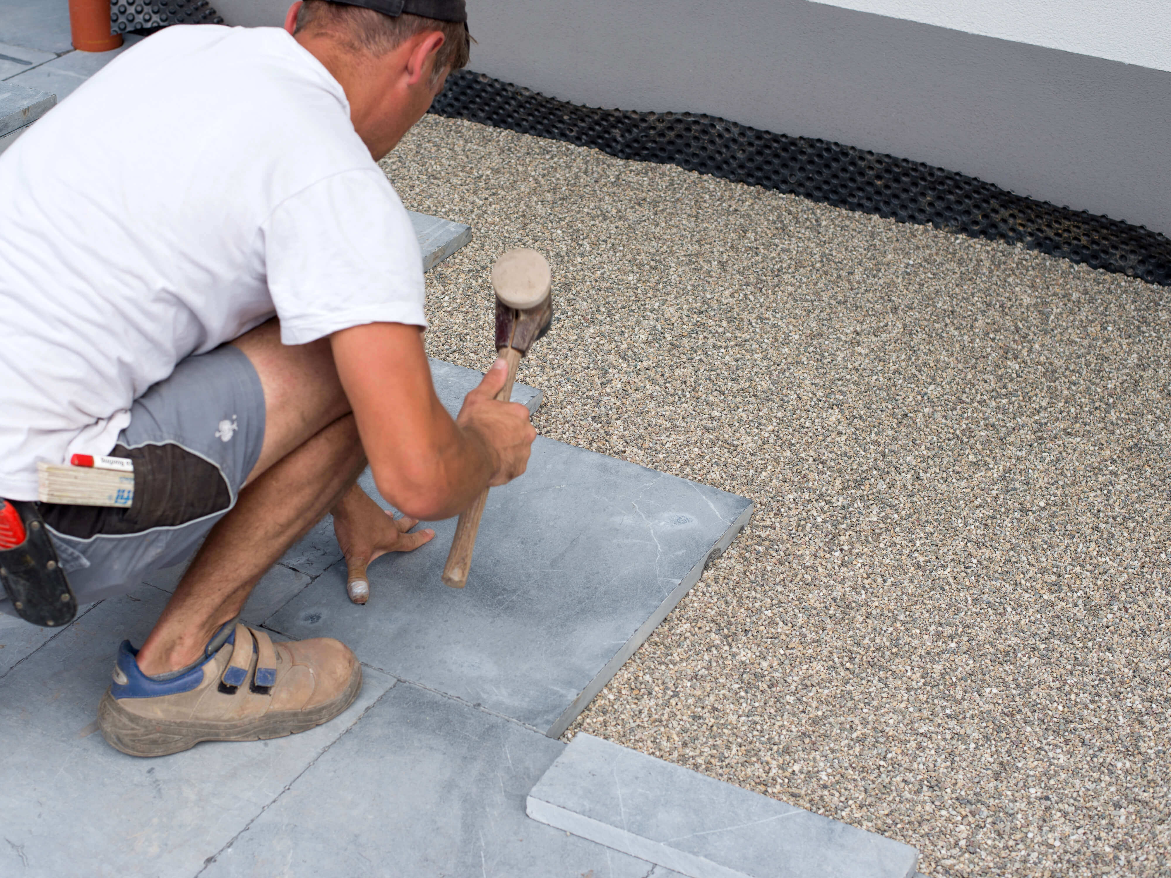 Mand lægger blåstensplader i et leje af skærver