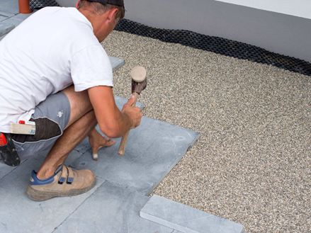 Mand lægger blåstensplader i et leje af skærver