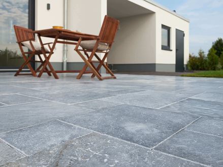 Udsigt i frøperspektiv over terrasse med marmorplader og træmøbler