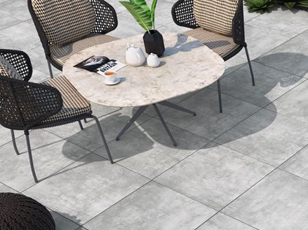 Terrasse med stol og lænestole, gulvbelægning i lyse porcelænsstentøjsfliser med betonlook