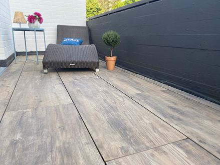 Altan med liggestol og terrassefliser af porcelænsstentøj med træeffekt som gulvbelægning