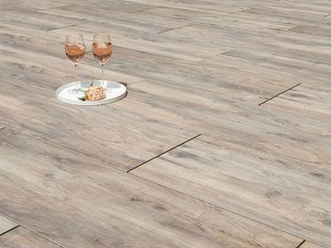 To vinglas og en blomst på terrassefliser i træ-effekt