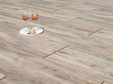 To vinglas og en blomst på terrassefliser i træ-effekt