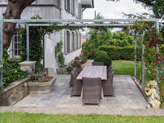 Kandla Grey sandstensplade på en terrasse med pergola og tilstødende græsplæne