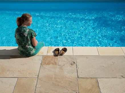 Pige sidder ved blå pool med sandstensplader Yellow Mint