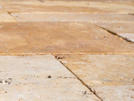 Detalje af travertinpladerne Gold i udendørsområdet set fra frøens perspektiv