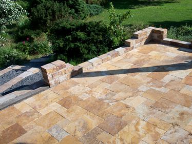 Gold travertinplade lagt i romersk bånd med naturstensmur og tilstødende have