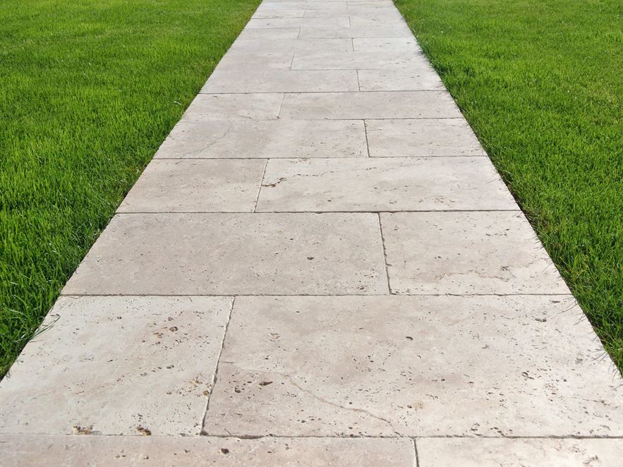 Gangbro lavet af travertinplader på græsplæne