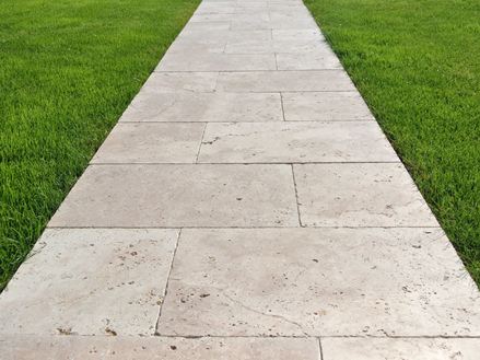 Gangbro lavet af travertinplader på græsplæne