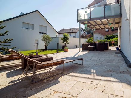 Solrig terrasse med to liggestole og medium travertingulv