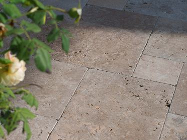 Den sene eftermiddagssol spiller på terrassens gulv, grene stikker ind i billedet fra højre