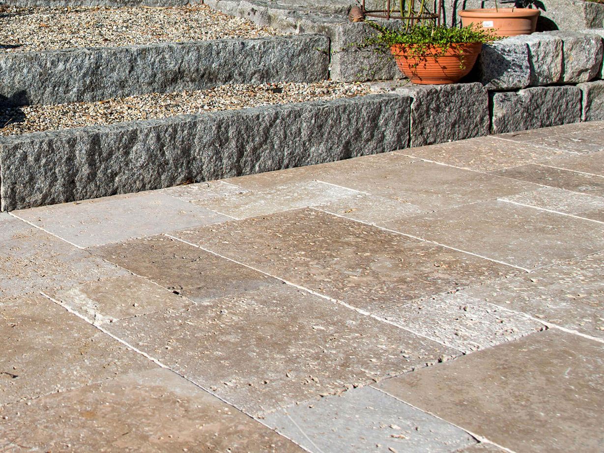 Travertin Noce: passer godt til landhusstilen Terrasse med naturstensplader af brun travertin, i baggrunden en trappe med granitsten