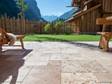 Terrassegulv med travertin rustic og træmøbler, i baggrunden en græsplæne og udsigt til bjergene