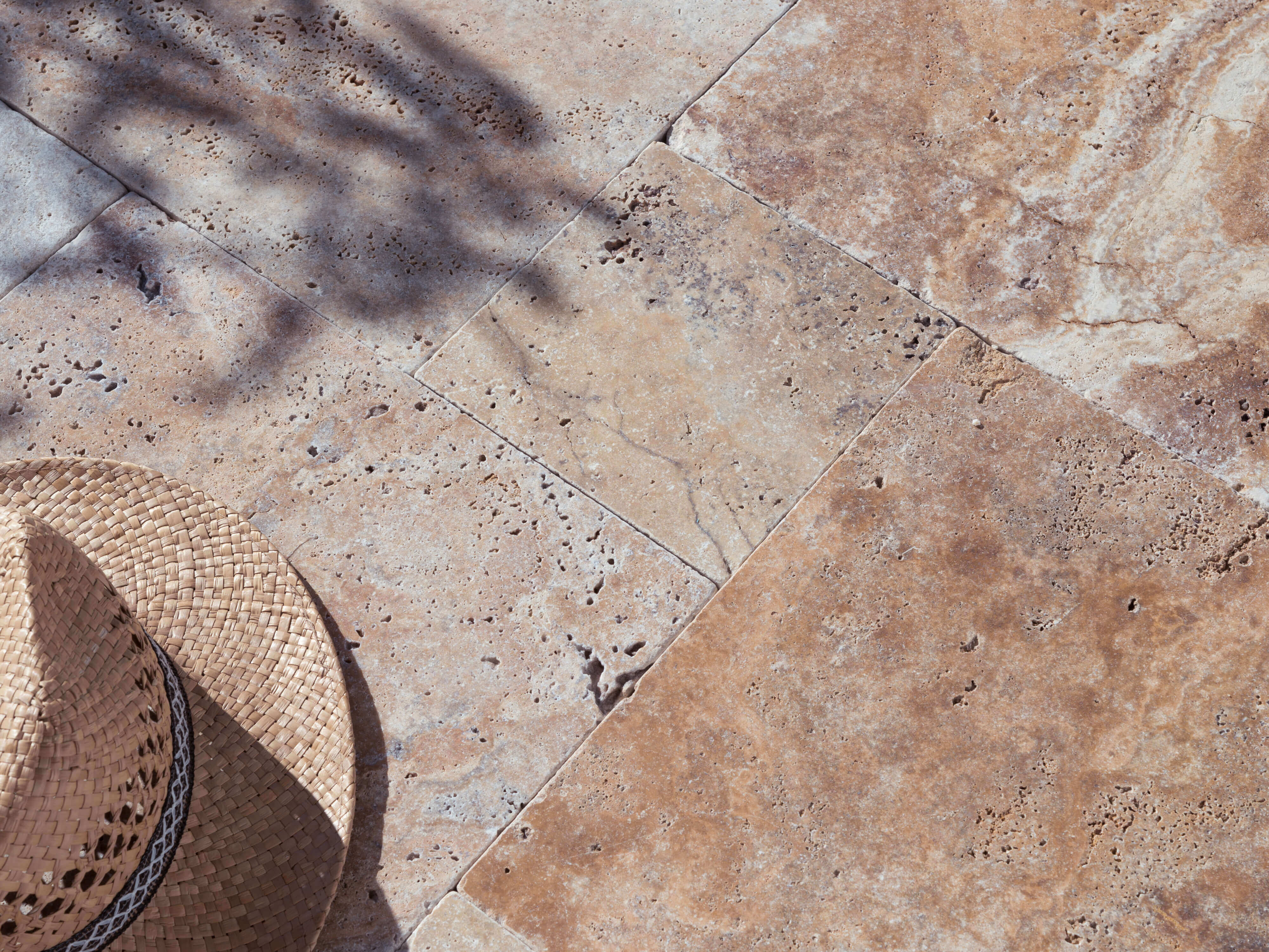 Travertin Scabas-terrasse i sollys med stråhat