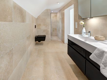 Badeværelse med moderne møbler og Cleopatra Light kalkstensfliser på gulv og vægge