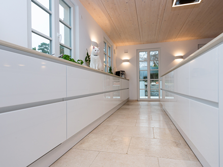 Åbent køkken med Cleopatra Light kalkstensfliser og hvide køkkenelementer