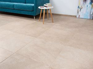 Fliser i kalkstenslook med turkisfarvet sofa og hvidt sidebord