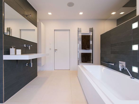 Moderne badeværelse med lyse kalkstensfliser på gulvet og mørk skifer på væggen