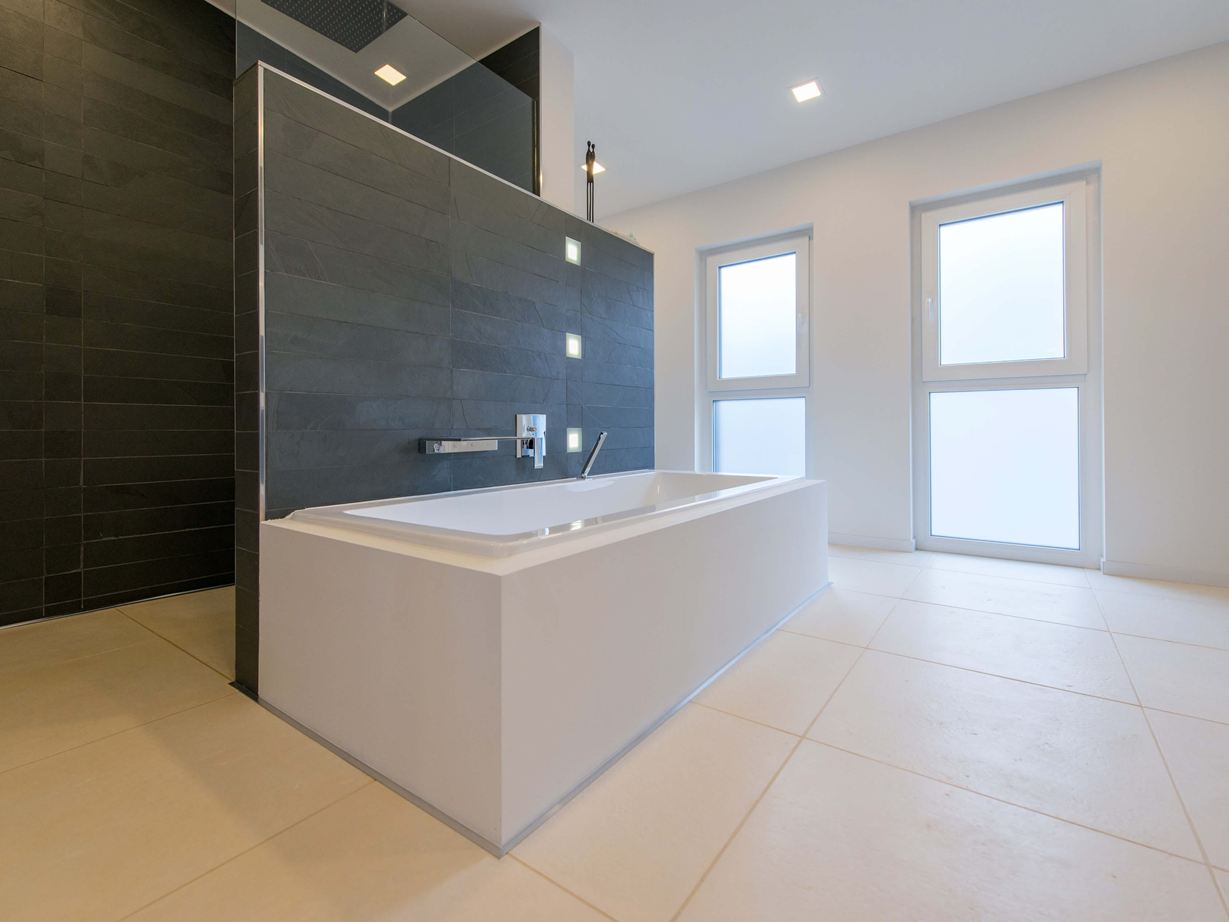 Badekar på lyse kalkstensfliser og skifer som vægbeklædning