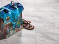 Fliser i calacatta-marmor med farverig strandtaske og sandaler