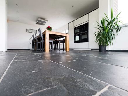 Frøperspektiv på Black Rustic skifergulv med træspisebord og plante i baggrunden