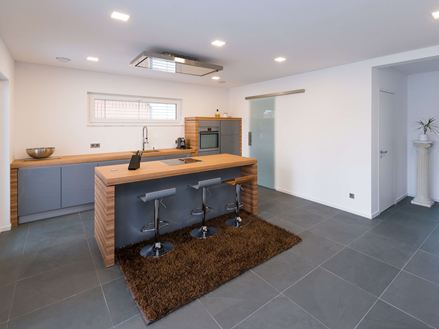 Køkken med træelementer og skiferfliser i blød grå som gulvbelægning