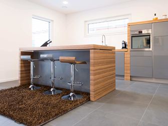 Køkken med åben bardisk, moderne træelementer og mørkt skifergulv