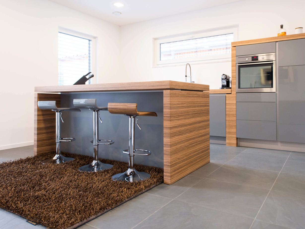 Køkken med åben bardisk, moderne træelementer og mørkt skifergulv