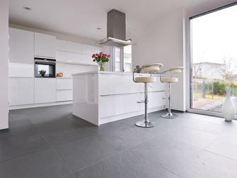 Hvidt køkken med metalelementer på grå skiferfliser med delt overflade