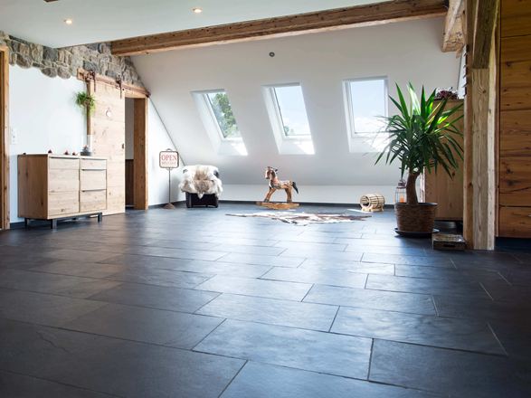 Værelse med antracitfarvet skifergulv og træmøbler, hvide vægge