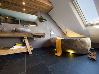 Rustikt badeværelse med badekar i stenlook og mørke skiferfliser som gulvbelægning