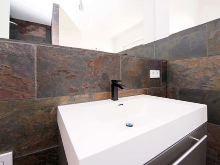 Fliser af påfugleskifer lagt bag en håndvask