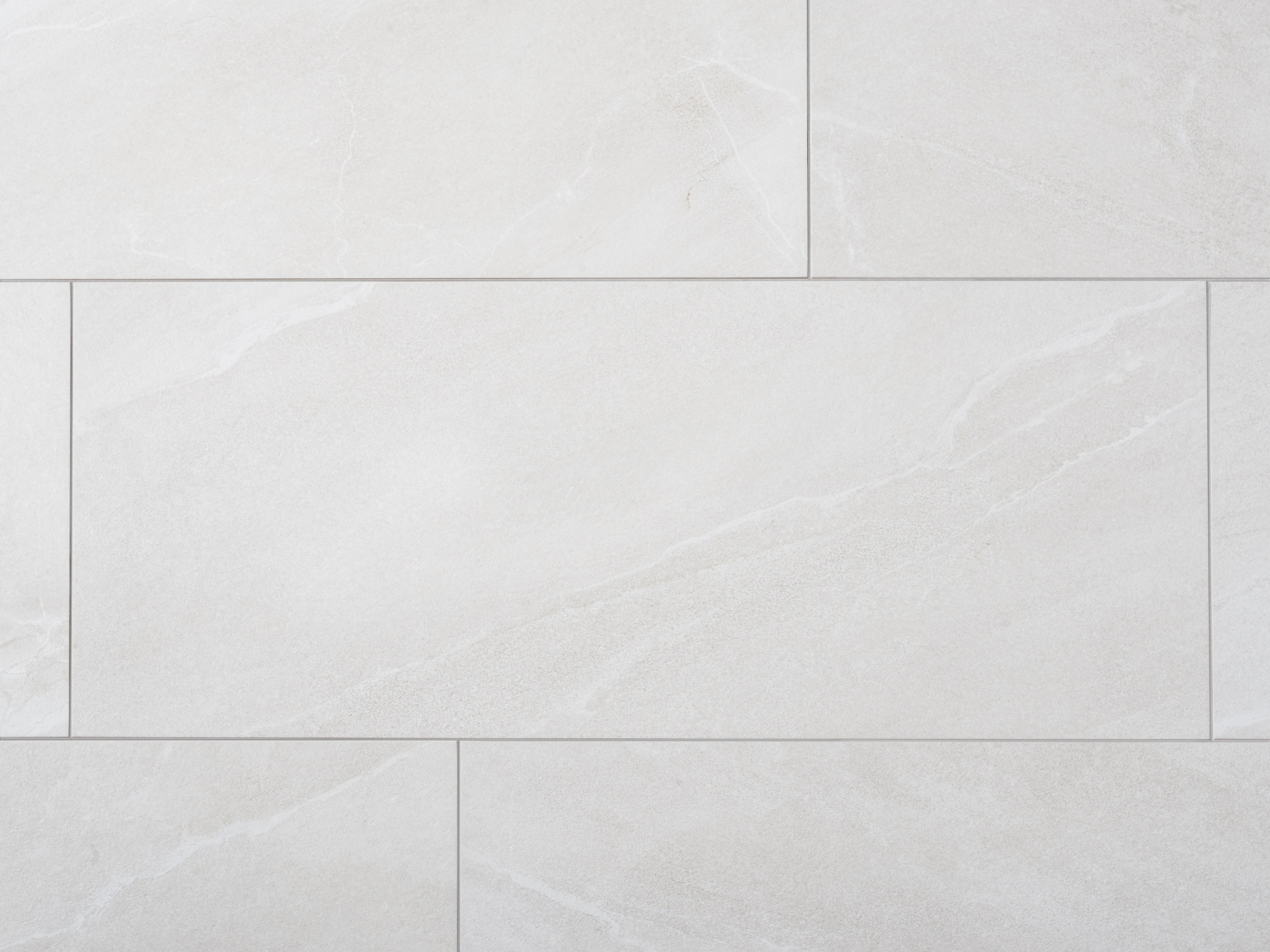 Nærbillede af lysegrå fliser i porcelænsstentøj med skiferlook og smalle fuger