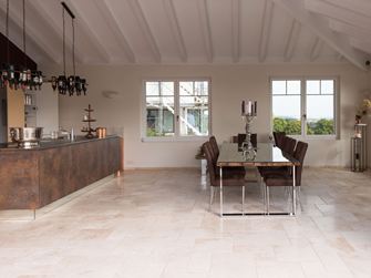 Light travertinfliser i romersk forbandt i et moderne køkken med spisebord og kogeø