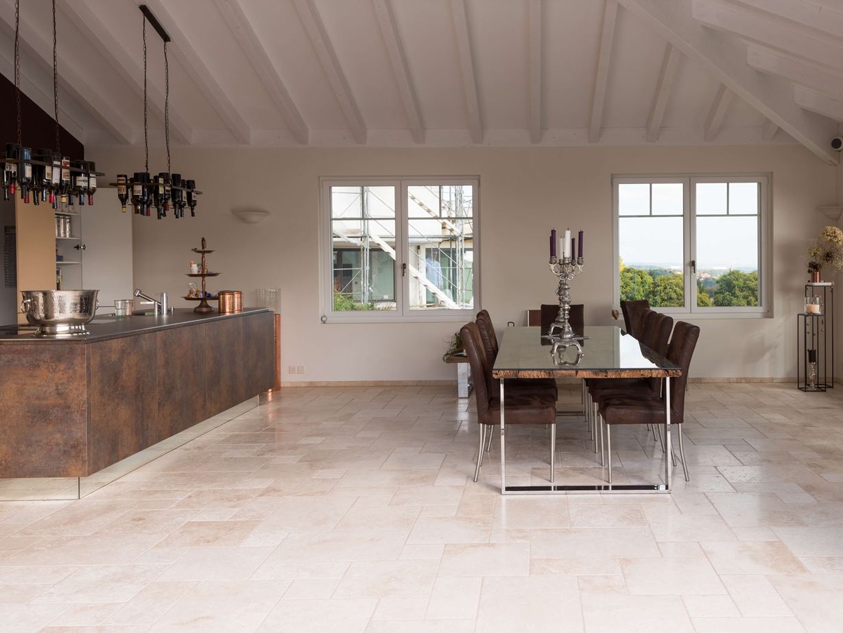 Moderne køkken møder middelhavsgulv. Light travertinfliser i romersk forbandt i et moderne køkken med spisebord og kogeø