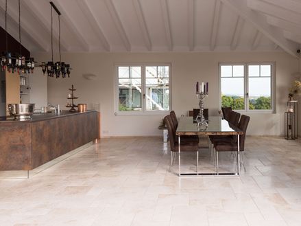 Light travertinfliser i romersk forbandt i et moderne køkken med spisebord og kogeø