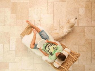 Dreng læser i en liggestol på Light travertinfliser lagt i et romersk bånd