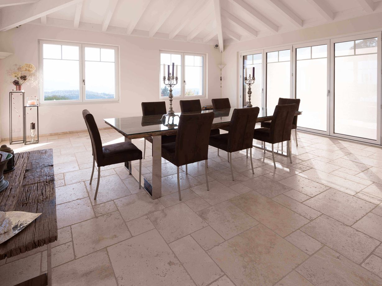 Travertin Light: lys og venlig effekt Spisestue med højt til loftet, bord og stole på travertin Light i romersk bindingsværk