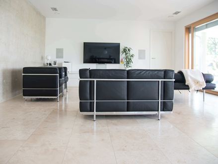 Stue med Travertin Classic Light fliser og moderne sort sofa