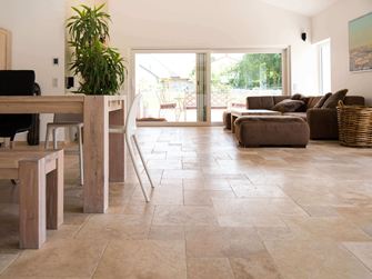 Stue med brun sofa, hvide vægge og medium travertinfliser i brun-beige som gulvbelægning