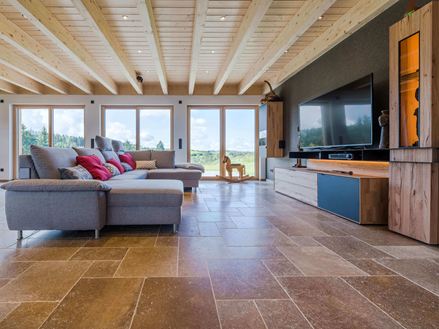 Stue med grå sofa og valnøddebrune Noce SELECT travertinfliser