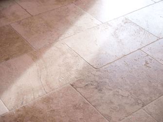 Rustikke fliser i travertin, set fra siden med lys og skygge