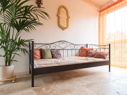 Soveværelse med seng, plante og rustik travertin på gulvet