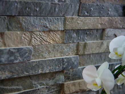 Hvide orkideer ved siden af væg med kvartsit Deoli Green lavet af individuelle slips