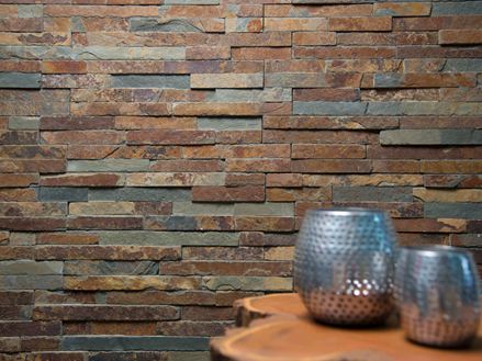 To vaser på et træbord foran en vægbeklædning af naturskifer i lyse nuancer