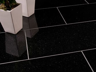 To hvide blomsterkrukker på mørke Star Galaxy-granitfliser med smalle, lyse fuger